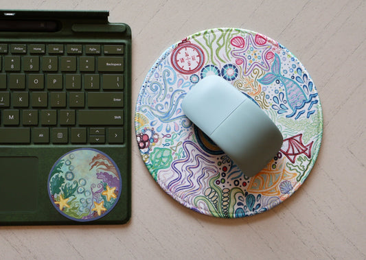 SLChristley Designs Oceanic Dreams mousepad with mouse and Under the Sea sticker on a keyboard, styled on a desk.