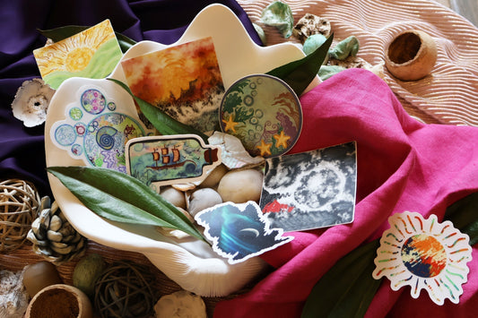 Collection of SLChristley Designs nature inspire stickers arranged inside a large sea-shell surrounded by purple, pink, and bright fabric.